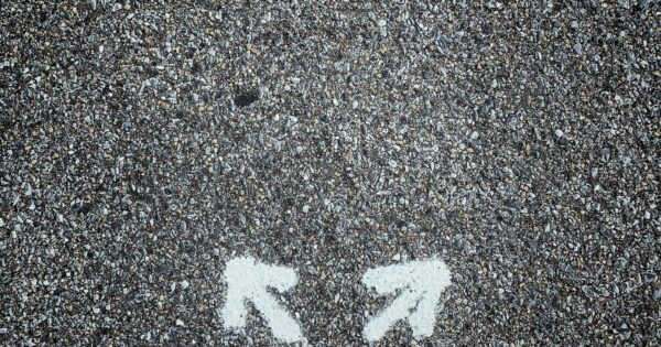 Trader standing at a crossroads representing the choices and decisions that can lead to trading success or failure