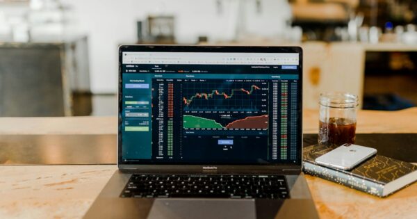 Laptop displaying financial charts in a trading workspace.