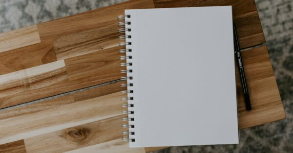 Spiral notebook on a wooden desk for planning and reviewing trades.